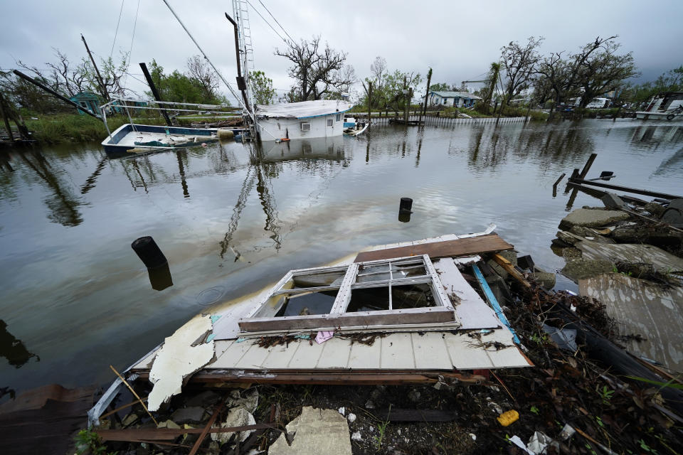 An oil sheen drifts between a sunken shrimp boat and pieces of a destroyed home along Bayou Pointe au Chien in the aftermath of Hurricane Ida in Pointe-aux-Chenes, La., Tuesday, Sept. 14, 2021. The wrecked boats, docks and processing equipment left by Hurricane Ida has some wondering what the future holds for Louisiana's seafood industry. (AP Photo/Gerald Herbert)