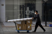 A delivery courier wearing a face mask pushes a cart along a pedestrian shopping street at the Wangfujing shopping district in Beijing, Saturday, Nov. 19, 2022. Performances have been suspended at one of Beijing's oldest and most renowned theaters amid a new wave of shop and restaurant closures in response to a spike in COVID-19 cases in the Chinese capital. (AP Photo/Mark Schiefelbein)