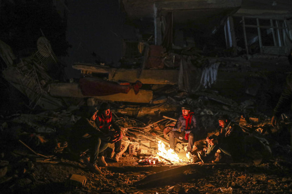 People sit by the debris of their collapsed house in Hatay, southern Turkey, Thursday, Feb. 9, 2023. Emergency crews made a series of dramatic rescues in Turkey on Friday, pulling several people, some almost unscathed, from the rubble, four days after a catastrophic earthquake killed more than 20,000. (AP Photo/Can Ozer)