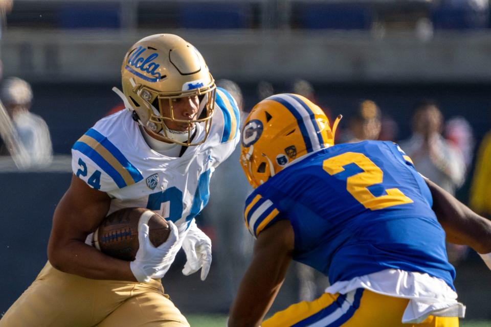 UCLA running back Zach Charbonnet runs the football against California safety Craig Woodson during the first quarter at California Memorial Stadium, Nov. 25, 2022 in Berkeley, Calif.