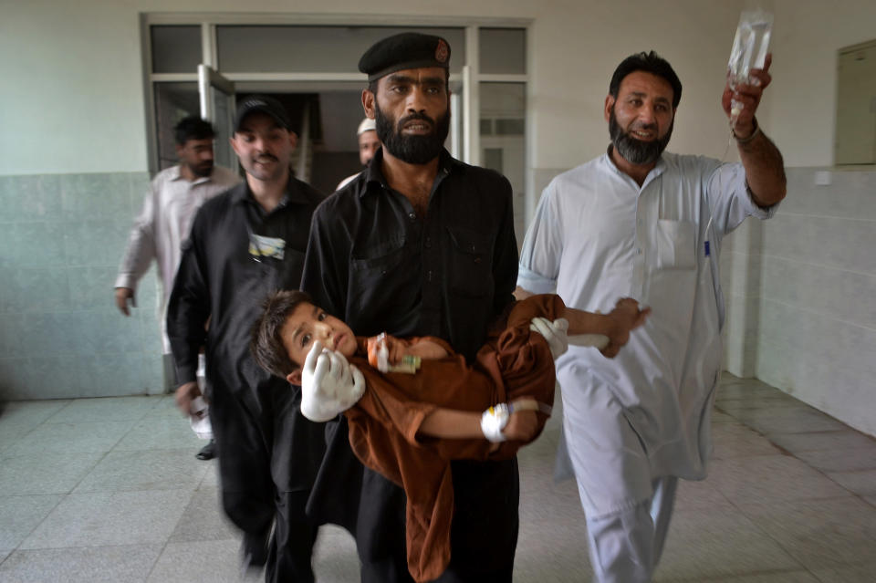 A security guard carries an injured child after a bomb explosion at Lady Reading Hospital in Peshawar, Pakistan, Sunday, May 11, 2014. A police official in Pakistan says a bomb blast targeting refugees registering with the government has killed several people in northwestern city of Peshawar. Faisal Mukhtar says the bombing Sunday on a soccer field also wounded many people. He says it happened as officials registered refugees from the nearby Khyber tribal region. (AP Photo/Mohammad Sajjad)