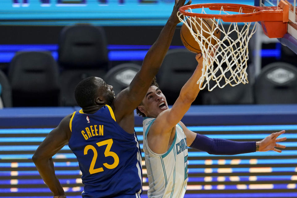 Golden State Warriors forward Draymond Green (23) defends against a shot-attempt by Charlotte Hornets guard LaMelo Ball during the first half of an NBA basketball game in San Francisco, Friday, Feb. 26, 2021. (AP Photo/Jeff Chiu)