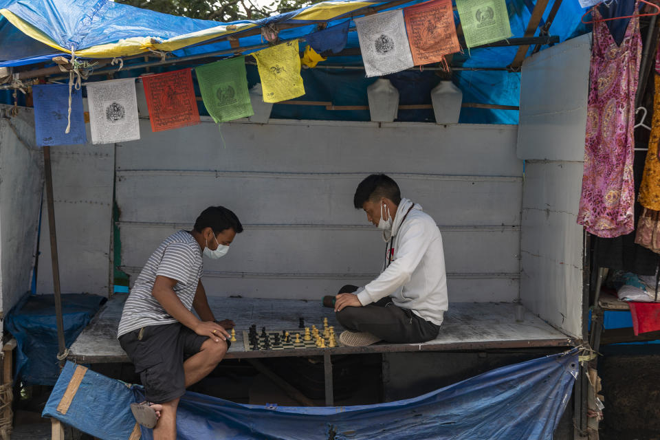 People wearing masks as a precaution against the coronavirus play chess at a roadside stall in Dharmsala, India, Monday, July 6, 2020. India has overtaken Russia to become the third worst-affected nation by the coronavirus pandemic. (AP Photo/Ashwini Bhatia)