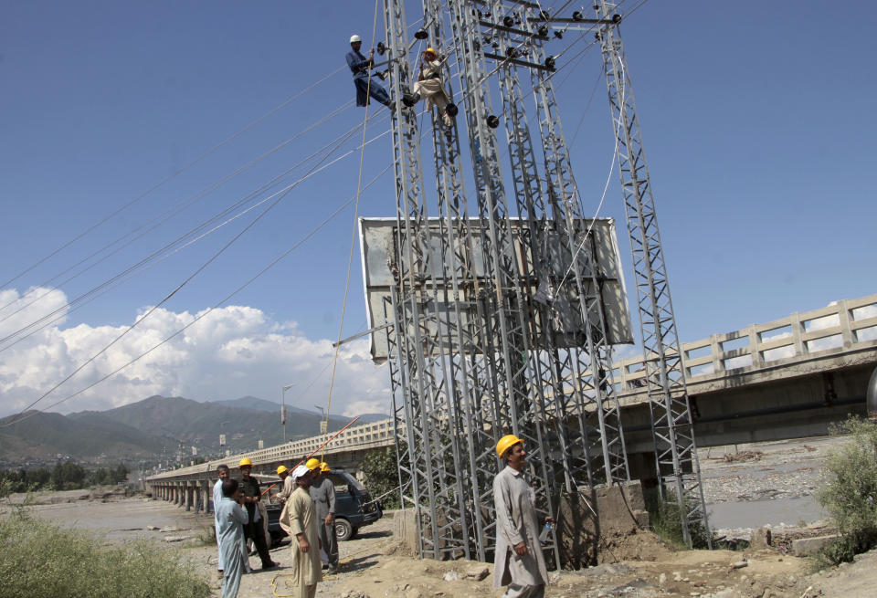 Government workers repair electricity cables to restore service to areas damaged by flooding, in Kanju, Swat Valley, Pakistan, Monday, Aug. 29, 2022. International aid was reaching Pakistan on Monday, as the military and volunteers desperately tried to evacuate many thousands stranded by widespread flooding driven by "monster monsoons" that have claimed more than 1,000 lives this summer. (AP Photo/Naveed Ali)