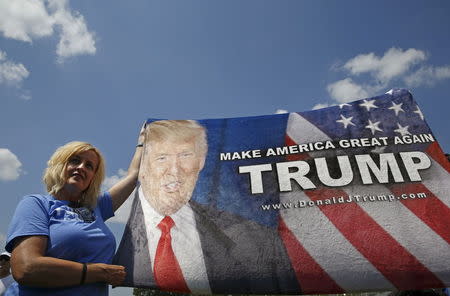 A supporter of Republican presidential candidate Donald Trump holds up a banner for his arrival near the Iowa State Fair in Des Moines, Iowa, United States, August 15, 2015. REUTERS/Jim Young