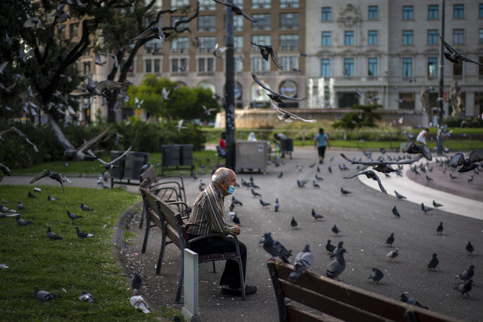 A man wearing a face mask to prevent the spread of coronavirus sits in a square in Barcelona, Spain, Wednesday Sept. 23, 2020. Spain is struggling to contain a second wave of the virus which has killed at least 30,000 people according to the country's health ministry. (AP Photo/Emilio Morenatti)