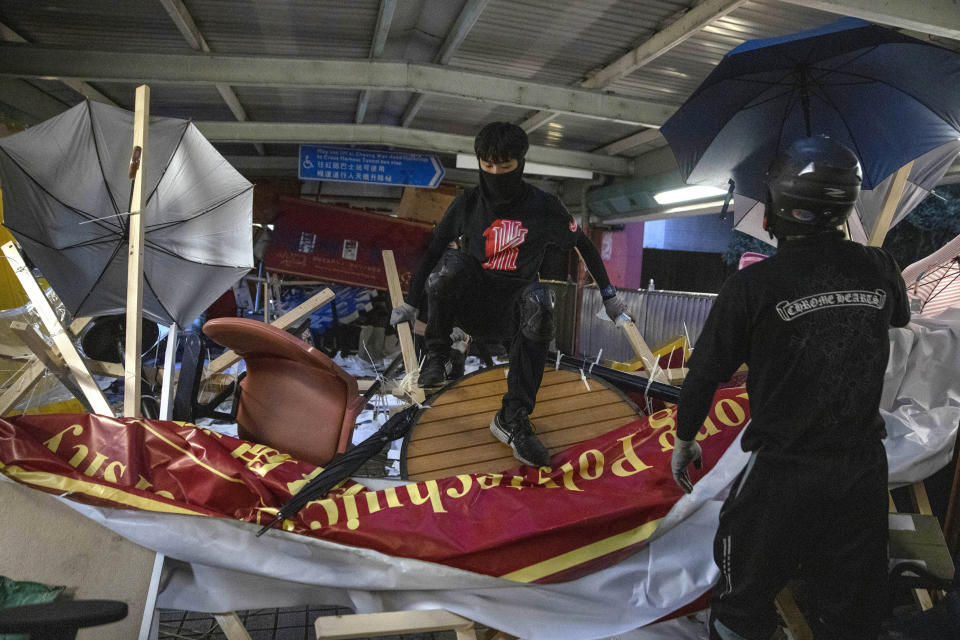 Protesters climb over a barricade on an overhead bridge near the Cross-Harbour Tunnel in Hong Kong, Thursday, Nov. 14, 2019. University students from mainland China and Taiwan are fleeing Hong Kong, while those from three Scandinavian countries have been moved or urged to leave as college campuses become the latest battleground in the city's 5-month-long anti-government unrest. (AP Photo/Ng Han Guan)