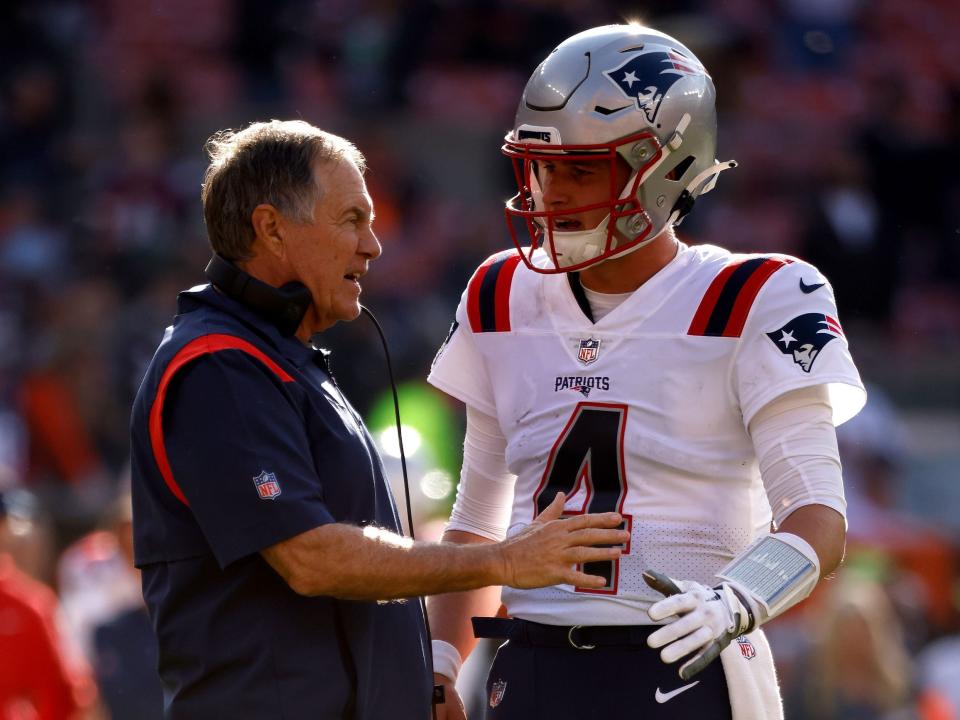 Bailey Zappe speaks with Bill Belichick during a game against the Cleveland Browns.