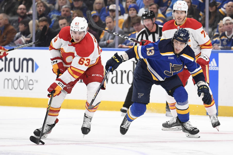 Calgary Flames' Adam Ruzicka (63) controls the puck from St. Louis Blues' Alexey Toropchenko (13) during the first period of an NHL hockey game Thursday, Jan. 12, 2023, in St. Louis. (AP Photo/Jeff Le)