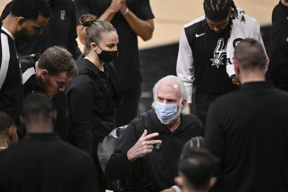 San Antonio Spurs coach Gregg Popovich, center, talks to players during a timeout in the first half of the team's NBA basketball game against the Toronto Raptors, Saturday, Dec. 26, 2020, in San Antonio. (AP Photo/Darren Abate)