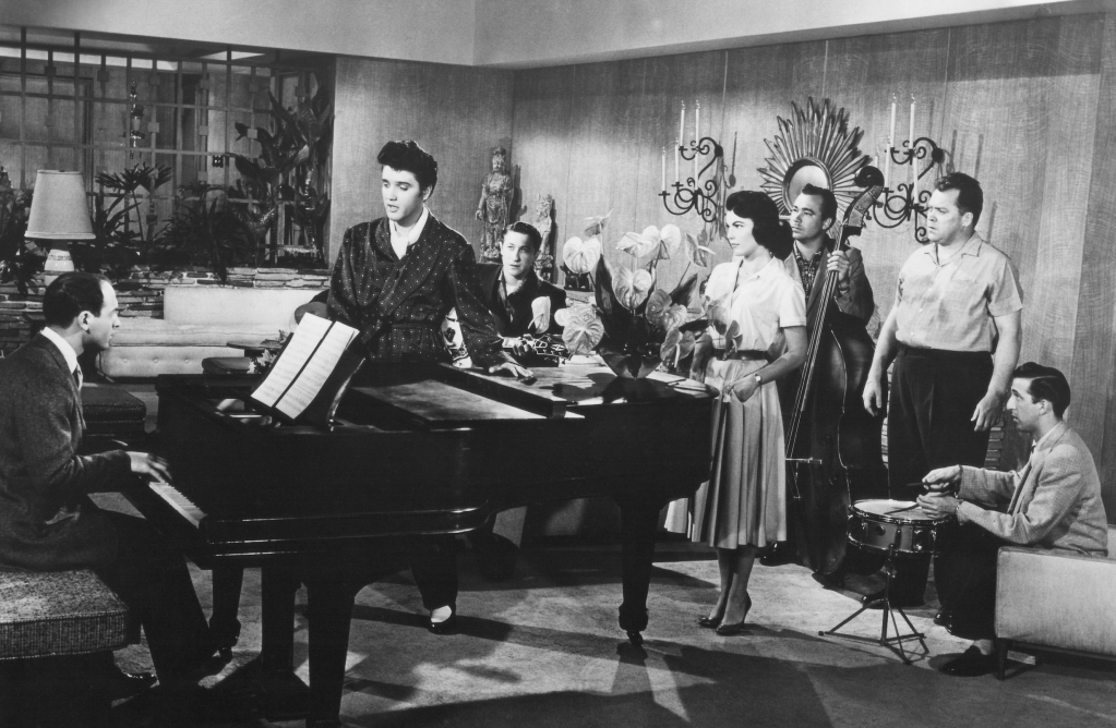 Mike Stoller plays the pianist in the film “Jailhouse Rock” with Elvis Presley. Also pictured: Scotty Moore, Judy Tyler, Bill Black, Mickey Shaughnessy and D.J. Fontana. - Credit: Courtesy Mike Stoller Archives