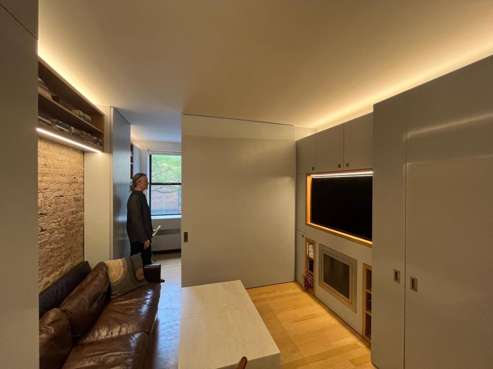 Robert Garneau stands in the doorway between the bedroom and the partitioned living room. 