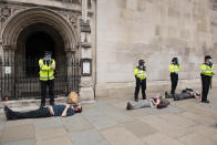 Police stand beside arrested protesters during an Extinction Rebellion demonstration in central London. The environmental campaign group has planned for marches to be held at several landmarks in the capital, before moving to Parliament Square in Westminster. (Photo by Stefan Rousseau/PA Images via Getty Images)