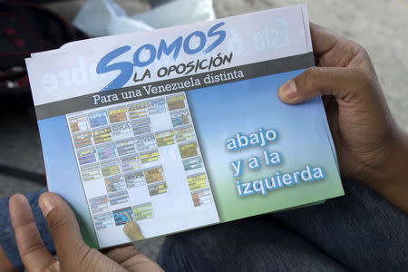 A flyer with information on how to vote for MIN Unidad Party is displayed by a woman in Caracas, November 3, 2015. REUTERS/Marco Bello