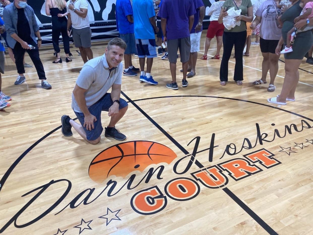 Michael Mignano poses next to the logo he created for the Darin Hoskins court, which was unveiled last August.
