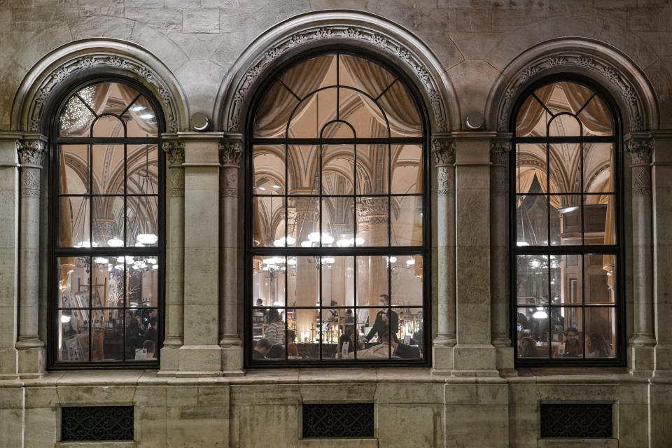 People sit in a cafe in Vienna, Austria, Sunday, Nov. 21, 2021. The Austrian government announced a nationwide lockdown that will start Monday and comes as average daily deaths have tripled in recent weeks and hospitals in heavily hit states have warned that intensive care units are reaching capacity.(AP Photo/Vadim Ghirda)