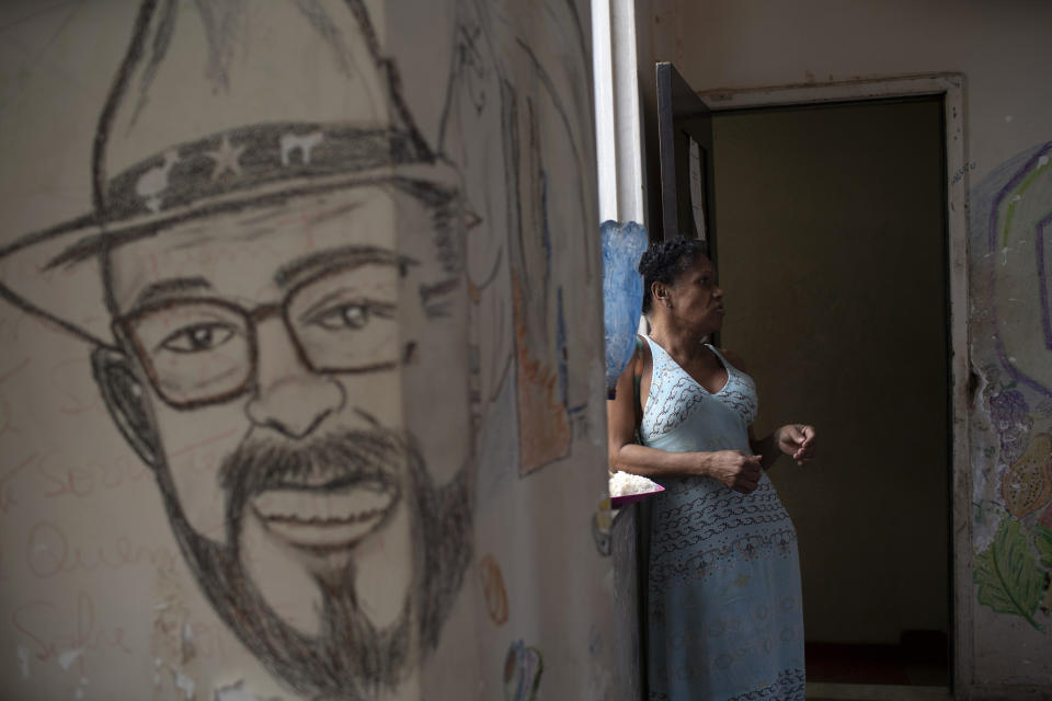 Claudinha is a resident of Casa Nem, a squat occupied by members of the LGBTQ community who are in self-quarantine as a protective measure against the new coronavirus, in Rio de Janeiro, Brazil, Wednesday, July 8, 2020. Claudinha is standing around the corner from a mural depicting Joao W. Nery, recognized as the first transgender man to have undergone sex-change surgery in Brazil. (AP Photo/Silvia Izquierdo)