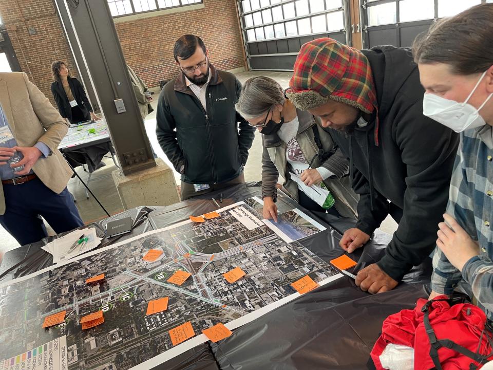 Breon Lewis, second from right, scans a map showing the I-375 project, which aims to turn the Detroit highway into a boulevard. Lewis lives in Grand Ledge, Michigan, near Lansing, but grew up in Detroit.