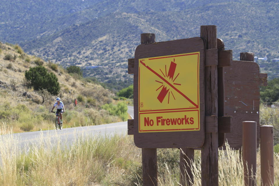 This June 30, 2023 image shows a sign prohibiting fireworks in the Sandia Mountains that border Albuquerque, New Mexico. U.S. Forest Service managers are urging people to use glow sticks and cans of aerosol party string as alternatives to fireworks, but some environmentalists say the string difficult to clean up and should not be used out in nature. (AP Photo/Susan Montoya Bryan)