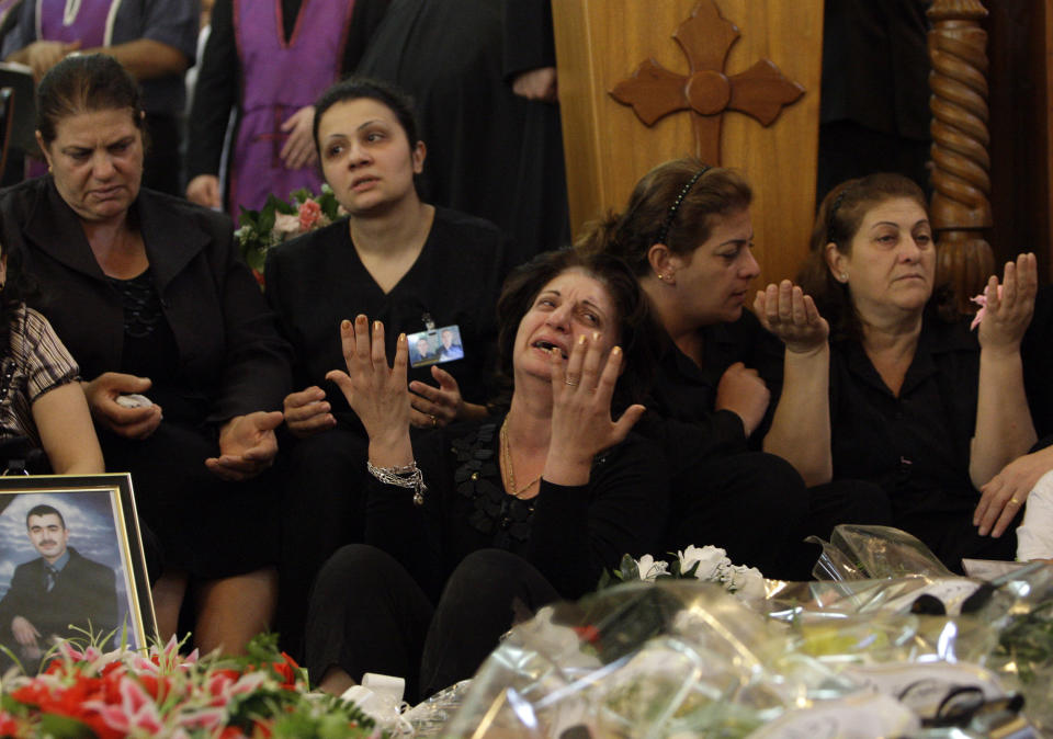 FILE - In this Tuesday, Nov 2, 2010 file photo, relatives grieve near the coffins of slain Christians at a funeral mass in Baghdad, Iraq. The victims were killed Sunday when gunmen stormed a church during mass and took the entire congregation hostage. The attack, claimed by an al-Qaida-linked organization, was the deadliest recorded against Iraq's Christians since the 2003 U.S.-led invasion unleashed a wave of violence against them. (AP Photo/Khalid Mohammed, File)