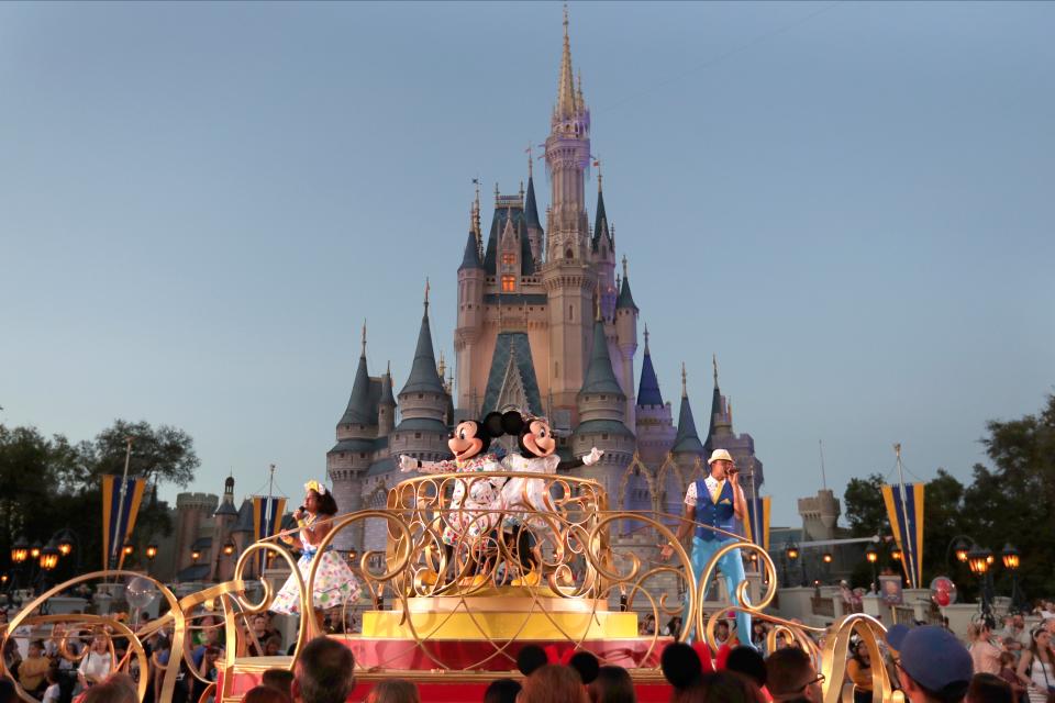 FILE - Mickey and Minnie Mouse perform during a parade as they pass by the Cinderella Castle at the Magic Kingdom theme park at Walt Disney World in Lake Buena Vista, Fla.  The theme park resort announced Tuesday, Feb. 15, 2022, that face coverings will be optional for fully-vaccinated visitors in all indoor and outdoor locations, with one exception. Face masks still will be needed for visitors ages 2 and older on enclosed transportation, such as the resort's monorail, buses and the resort's sky gondola. (AP Photo/John Raoux, File)