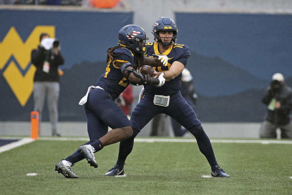 West Virginia quarterback JT Daniels (18) hands the ball to West Virginia running back Tony Mathis Jr. (24) during the first half of an NCAA college football game against Oklahoma in Morgantown, W.Va., Saturday, Nov. 12, 2022. (AP Photo/Kathleen Batten)