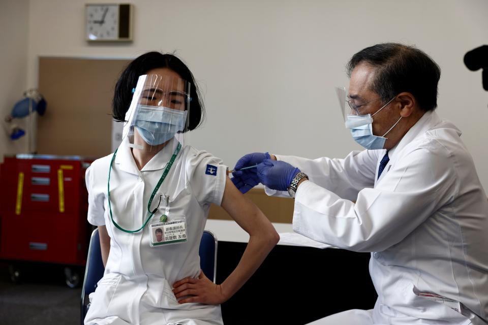 In this Feb. 17, 2021, file photo, a medical worker receives a dose of Pfizer's COVID-19 vaccine at Tokyo Medical Center in Tokyo.