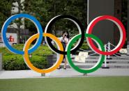 FILE PHOTO: A woman wearing a protective mask amid the coronavirus disease (COVID-19) outbreak, takes a picture of the Olympic rings in front of the National Stadium in Tokyo