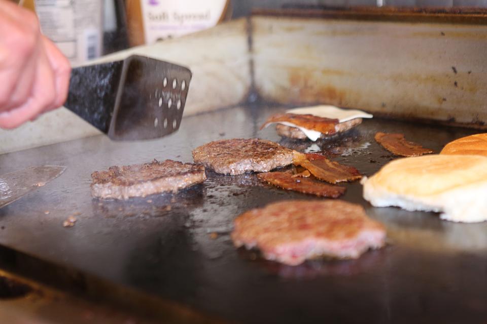 Hamburgers and bacon cooking on the grill at Angelo's Luncheonette in Wilmington.