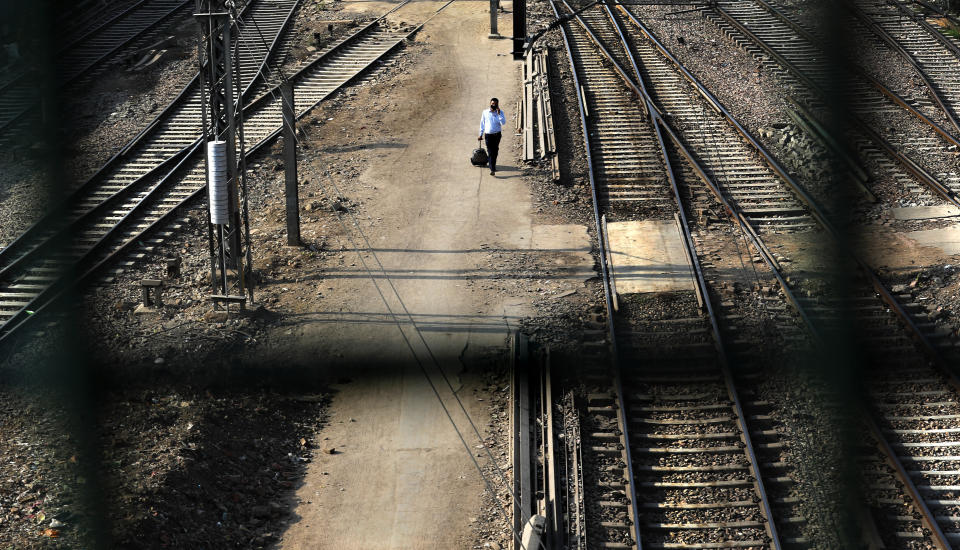 A passenger walks between railway tracks at New Delhi Railway station during a lockdown amid concerns over the spread of Coronavirus, in New Delhi, India, Monday, March 23, 2020. Authorities have gradually started to shutdown much of the country of 1.3 billion people to contain the outbreak. For most people, the new coronavirus causes only mild or moderate symptoms. For some it can cause more severe illness. (AP Photo/Manish Swarup)