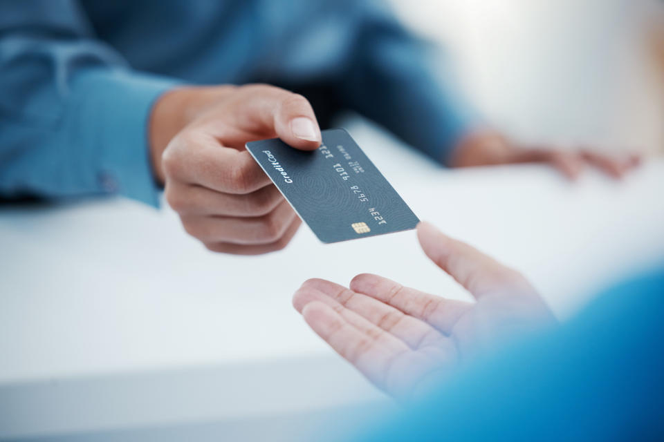 A person hands over a credit card to another individual