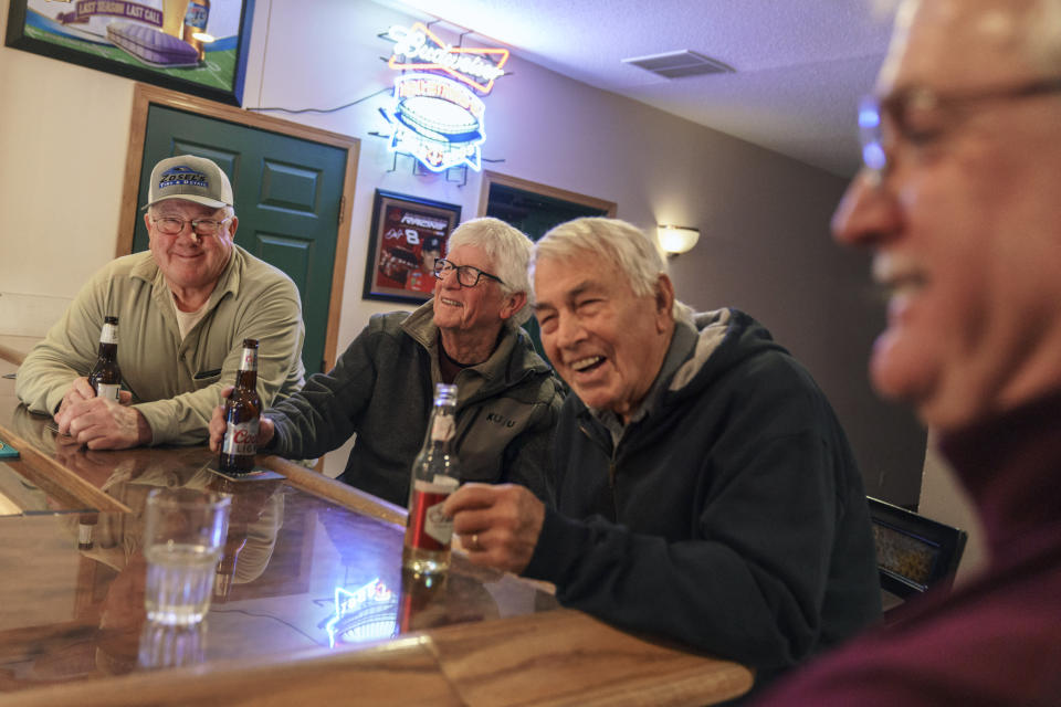 Reed Anfinson, right, who is often tagged as the liberal publisher of the The Swift County Monitor-News, meets up at a bar with John Zosel, from left, Mick Abner and Bill Harrison, part of a weekly gathering made up of mostly Republicans, in Benson, Minn., Tuesday, Nov. 30, 2021. It can be easy, looking around Benson, to think it is a land that time forgot. Bartenders often greet customers by name. The town’s cafes feel like high school lunchrooms, with people wandering between tables to say hello. (AP Photo/David Goldman)
