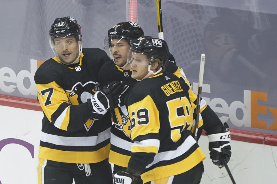 Pittsburgh Penguins Sidney Crosby, center, is greeted by Bryan Rust (17) and Jake Guentzel (59) after scoring against the New Jersey Devils during the first period of an NHL hockey game, Sunday, March 21, 2021, in Pittsburgh. (AP Photo/Keith Srakocic)