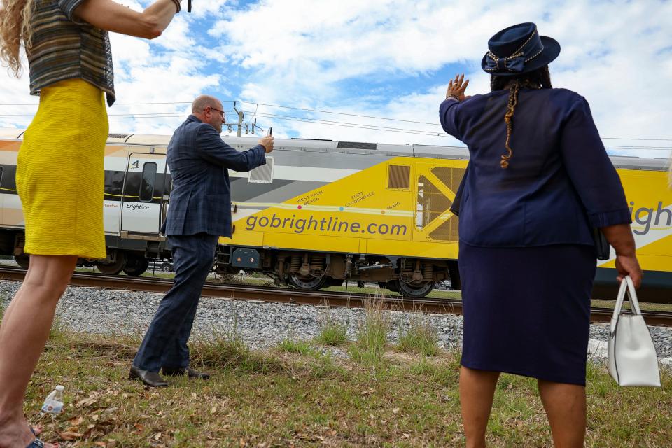 Colleen Pachowicz (left), Stuart City Commissioner Troy McDonald (center) and Stuart City Commissioner Eula Clarke wave and video record a Brightline passing the site of the company's first Treasure Coast railroad station following the official announcement ceremony at 500 Southeast Flagler Ave. in downtown Stuart on Monday, March 4, 2024. U.S. Rep. Brian Mast, R-Fort Pierce, and county and city leaders spoke during the event.