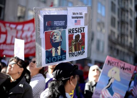 Protesters hold up signs during a march and rally against the United States President-elect Donald Trump in Los Angeles, California, U.S. December 18, 2016.REUTERS/Kevork Djansezian