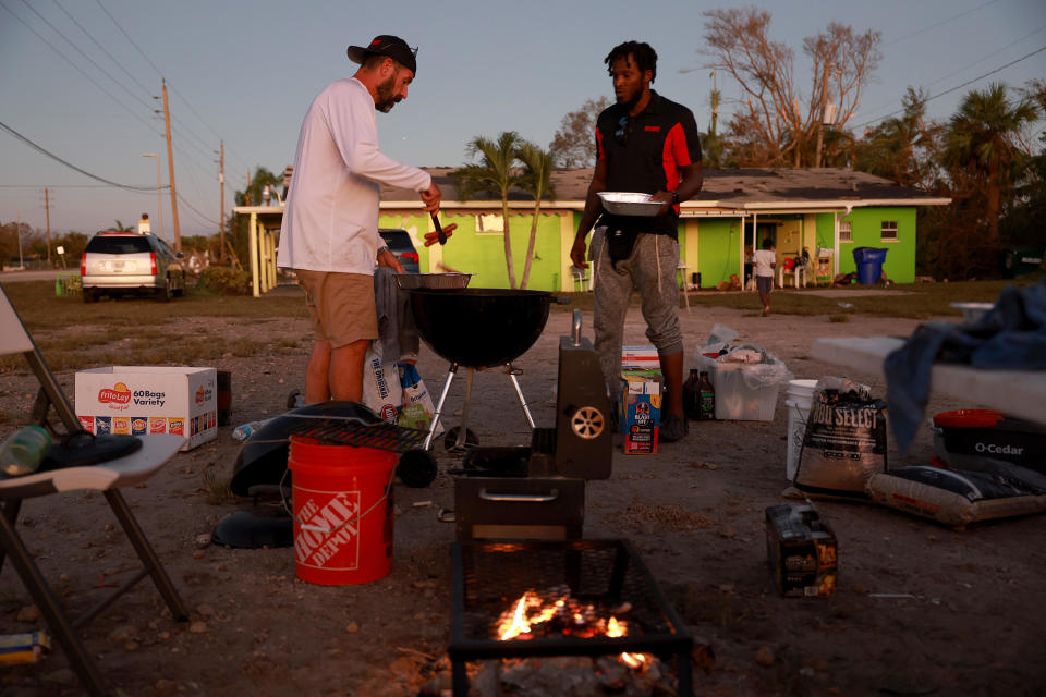 An unidentified volunteer and Ken Diesel, right, help cook food for people in need in Fort Myers, Florida, on Sept. 30, 2022. / Credit: Getty Images