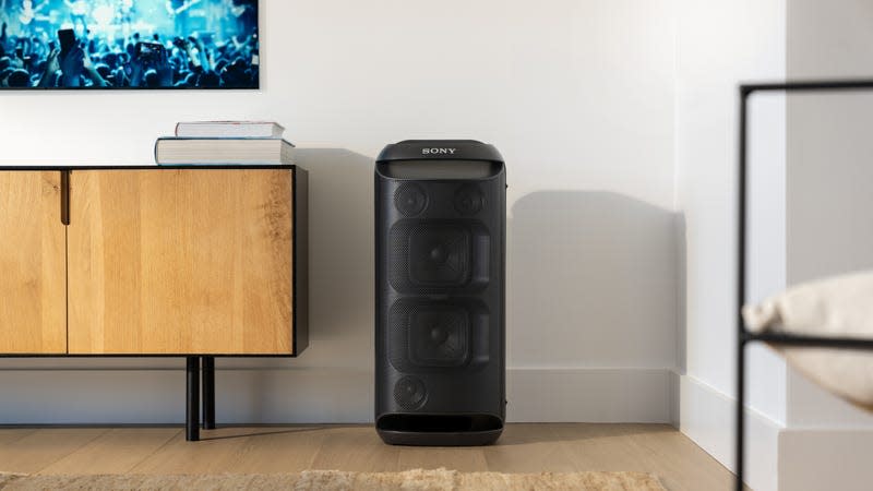 The Sony SRS-XV800 speaker standing against a wall next to a wall-mounted television.