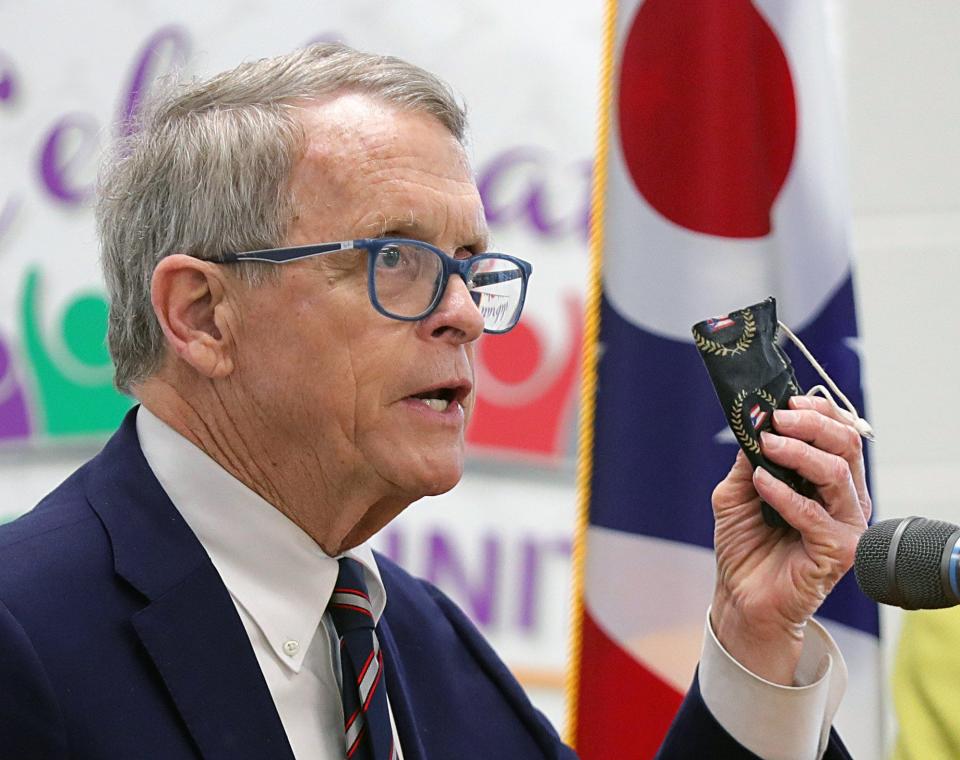 Gov. Mike DeWine holds up his mask as he fields questions regarding Senate Bill 22 during a press conference at a vaccine clinic, Friday, March 26, 2021, in Canton, Ohio. [Jeff Lange/Beacon Journal]