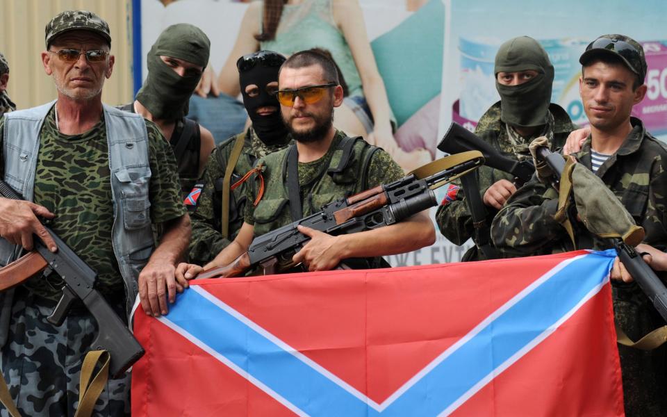 Pro-Russian militants pose on July 13, 2014 with a 'Novorossiya' flag in Donetsk, eastern Ukraine, in July 2014 - Credit: DOMINIQUE FAGET/AFP