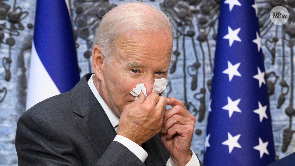 In this file photo taken on July 14, 2022, US President Joe Biden wipes his nose after signing the guest book while visiting Israel's President Isaac Herzog at Beit HaNassi, the presidential residence in Jerusalem. - Biden said on July 21, 2022, he was "doing great" after the White House announced he had contracted Covid-19 and was isolating with mild symptoms. "Folks, I'm doing great," Biden tweeted, above a picture showing him seated at his desk, smiling, with smartphones and documents laid out in front of him. "Thanks for your concern," the president wrote, adding: "Keeping busy!" (Photo by MANDEL NGAN / AFP) (Photo by MANDEL NGAN/AFP via Getty Images)