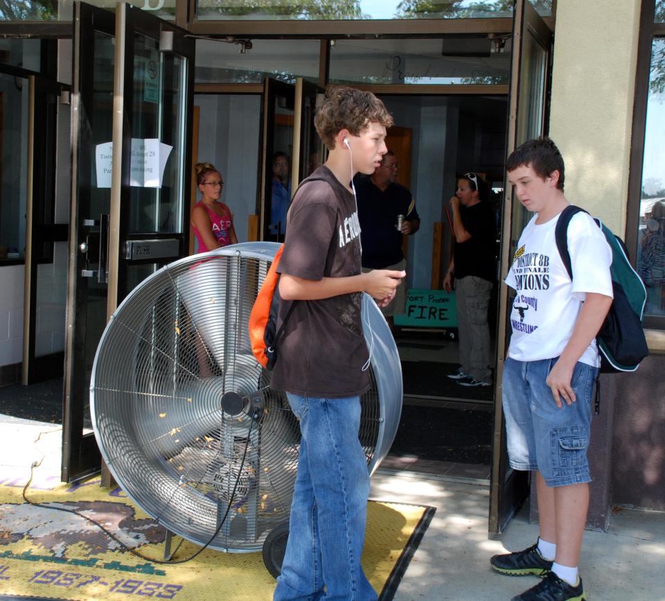 Chandler Lacher, left, and Cody Clarambeau, both 8th graders, stand near a fan blowing air into a school building in Fort Pierre, S.D., on Wednesday, Aug. 29, 2012, after the Stanley County School District closed early because of extreme heat. More than two dozen South Dakota schools let students go home early Wednesday because temperatures topping 100 degrees made classrooms that are not air conditioned unbearable. (AP Photo/Chet Brokaw)