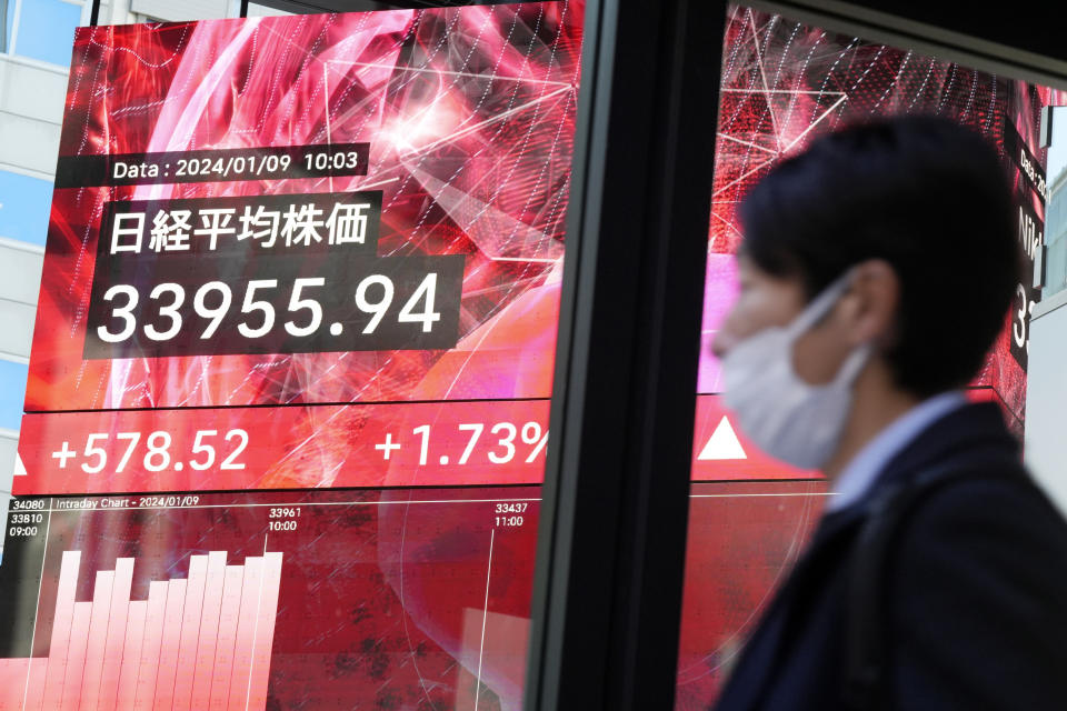 A person walk in front of an electronic stock board showing Japan's Nikkei 225 index at a securities firm Tuesday, Jan. 9, 2024, in Tokyo. (AP Photo/Eugene Hoshiko)
