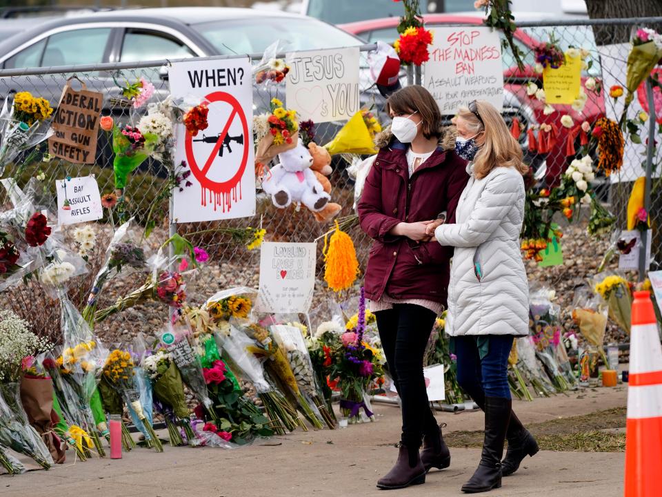 Mourners walk along fence near grocery store