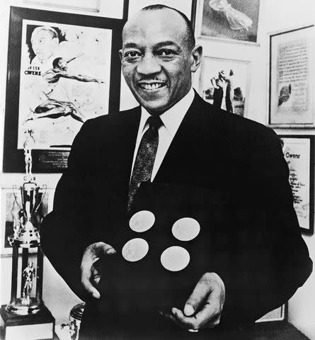 <p>Hulton Archive/Getty</p> Jesse Owens poses with the four gold medals he won at the 1936 Berlin Olympics in 1955.