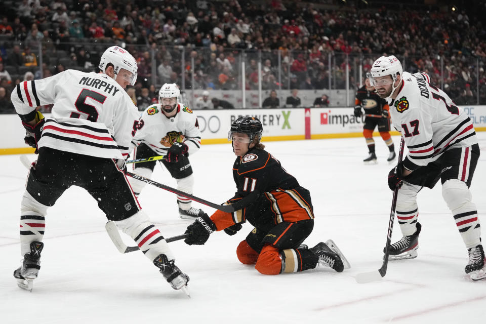 Anaheim Ducks' Trevor Zegras (11) is defended by Chicago Blackhawks' Connor Murphy (5) and Jason Dickinson (17) during the first period of an NHL hockey game Monday, Feb. 27, 2023, in Anaheim, Calif. (AP Photo/Jae C. Hong)