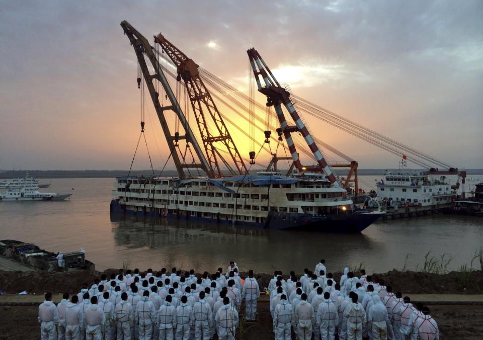 Rescue workers stand on the river bank as the capsized cruise ship Eastern Star is pulled out of the Yangtze against sunset, in Jianli