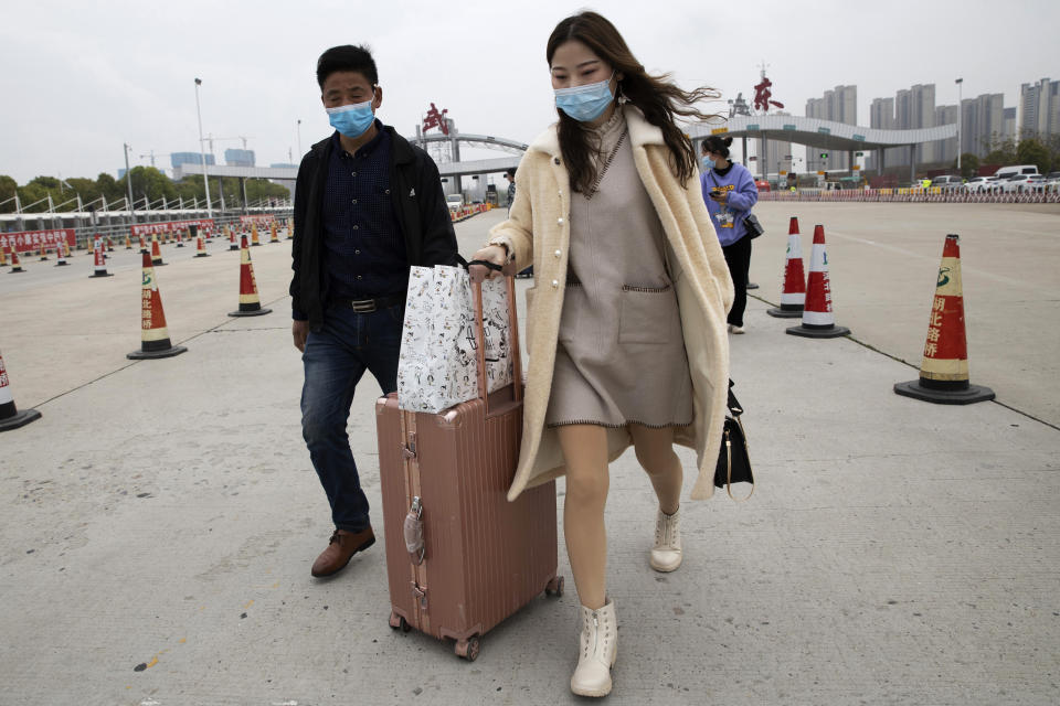 In this Thursday, April 2, 2020, photo, a woman walks from the expressway gate at the border of Wuhan city in central China's Hubei province. Millions of Chinese workers are streaming back to factories, shops and offices but many still face anti-coronavirus controls that add to their financial losses and aggravation. In Wuhan police require a health check and documents from employers for returning workers. (AP Photo/Ng Han Guan)