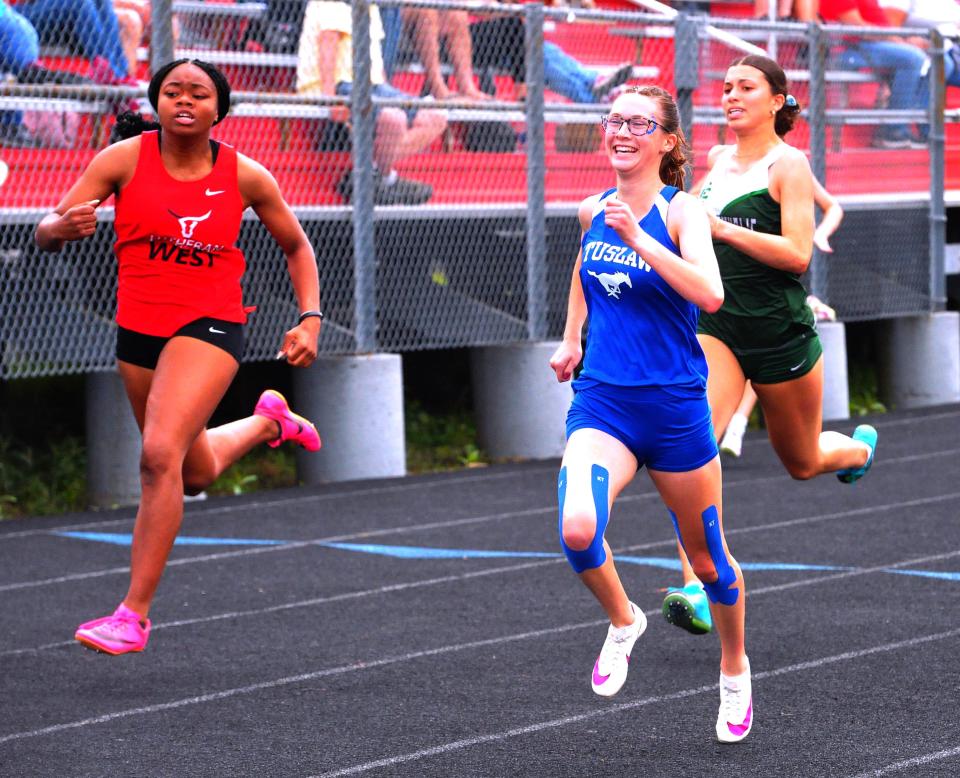Tuslaw's Hailey Wood flashes a winner's smile when she realizes she is going to win the 200-meter dash.