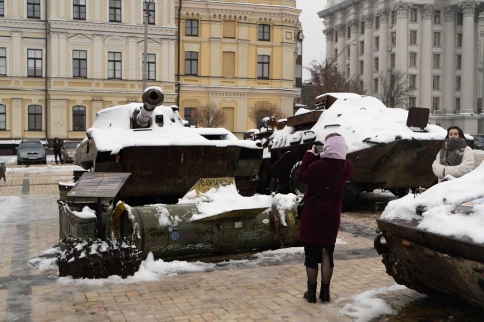 A woman takes a photo of a destroyed Russian BTR armored personnel carrier on display at St Michael’s Square. (Photo via Bennett Murray)