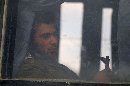 A rebel fighter holds his weapon on a bus, as rebel fighters and their families evacuate from the besieged Waer district, after an agreement was reached between rebels and Syria's army, in Homs, Syria May 20, 2017. REUTERS/Omar Sanadiki